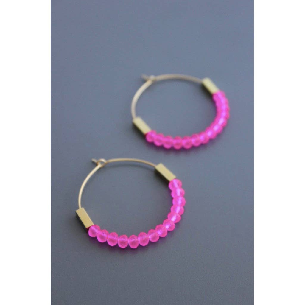 Pair of pink beaded hoop earrings on a gray background