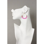 Pink beaded hoop earring on a white mannequin ear against a gray background