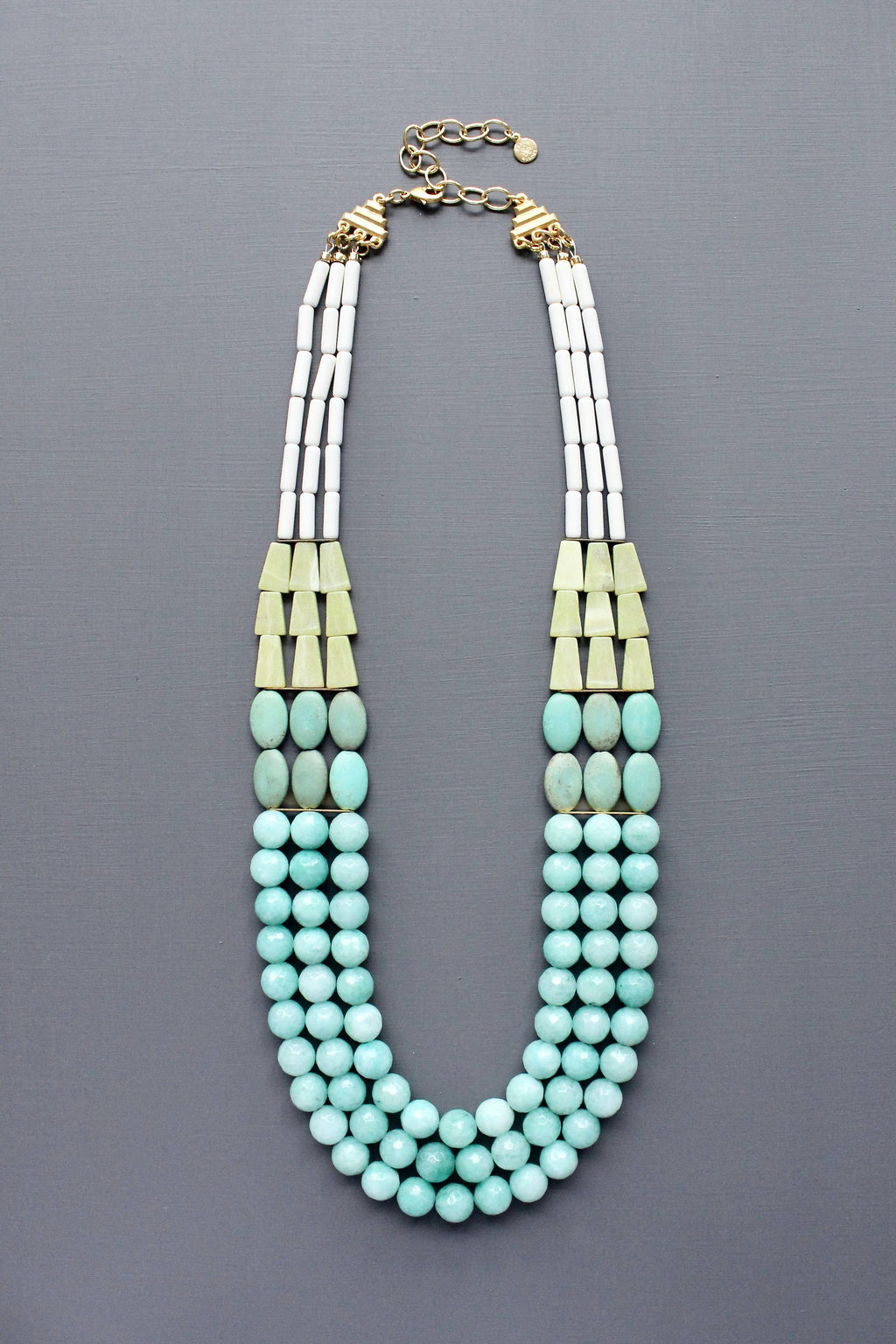 Triple strand Necklace with turquoise beads and amazonite with gold accents flatlay on grey background