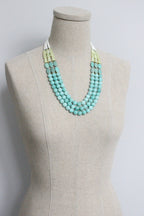Turquoise beaded necklace on a mannequin bust against a plain background