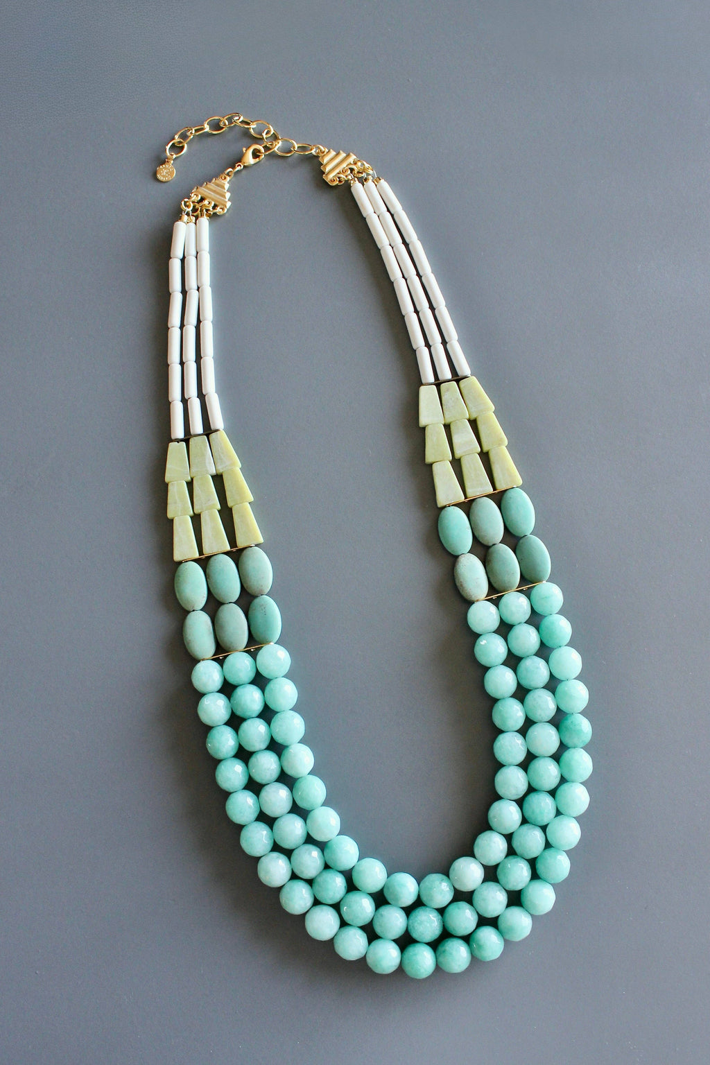 Necklace with turquoise beads and gold accents on a gray background
