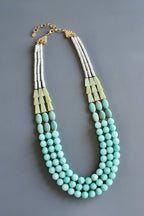 Necklace with turquoise beads and gold accents on a gray background