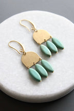Gold earrings with turquoise beads on a marble surface