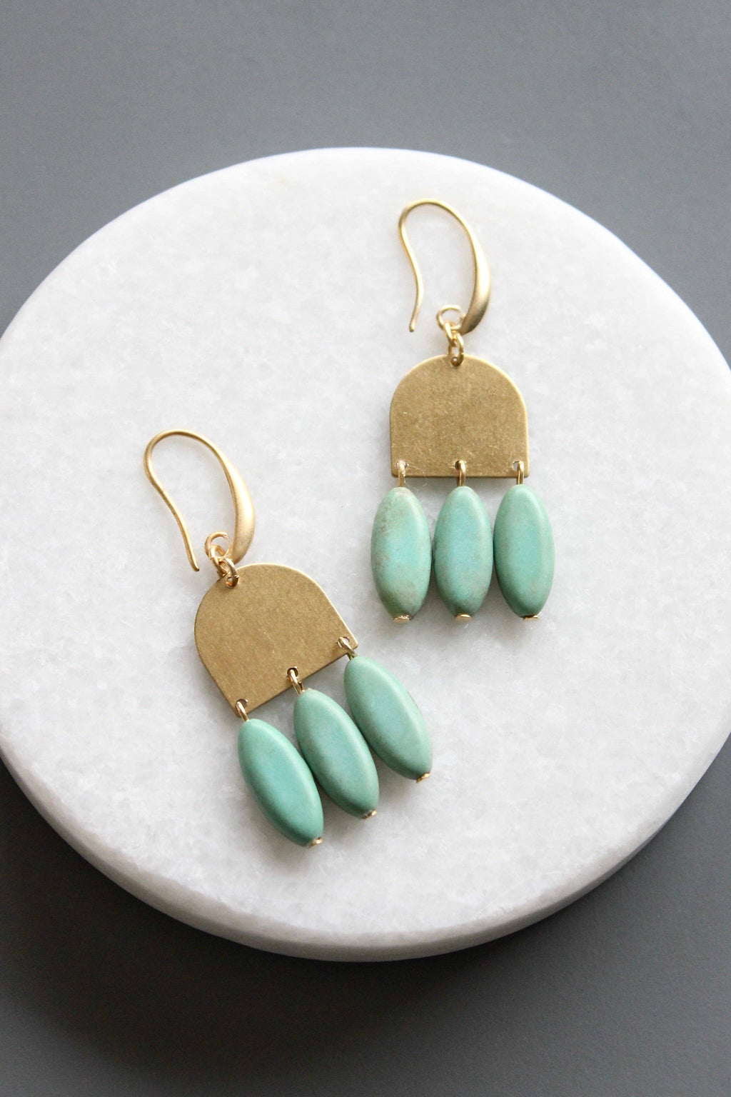 Gold and turquoise earrings on a marble surface