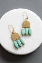 Gold and turquoise earrings on a marble surface