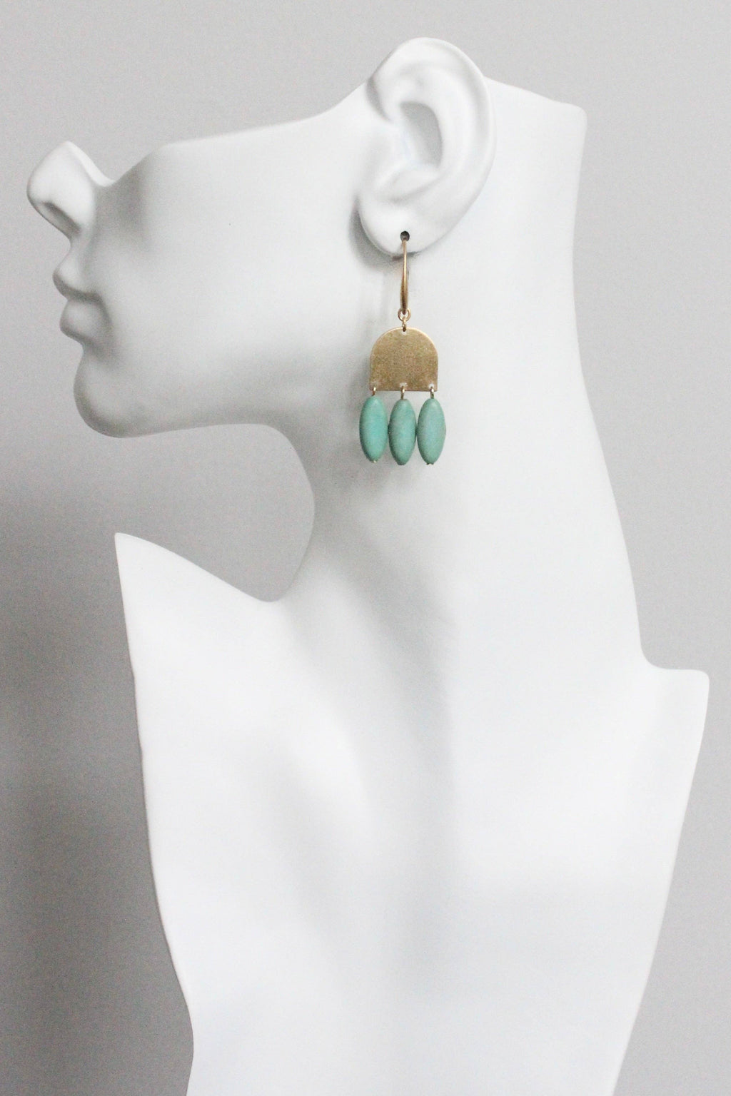 Earring displayed on a white mannequin bust with a gray background