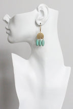 Earring displayed on a white mannequin bust with a gray background