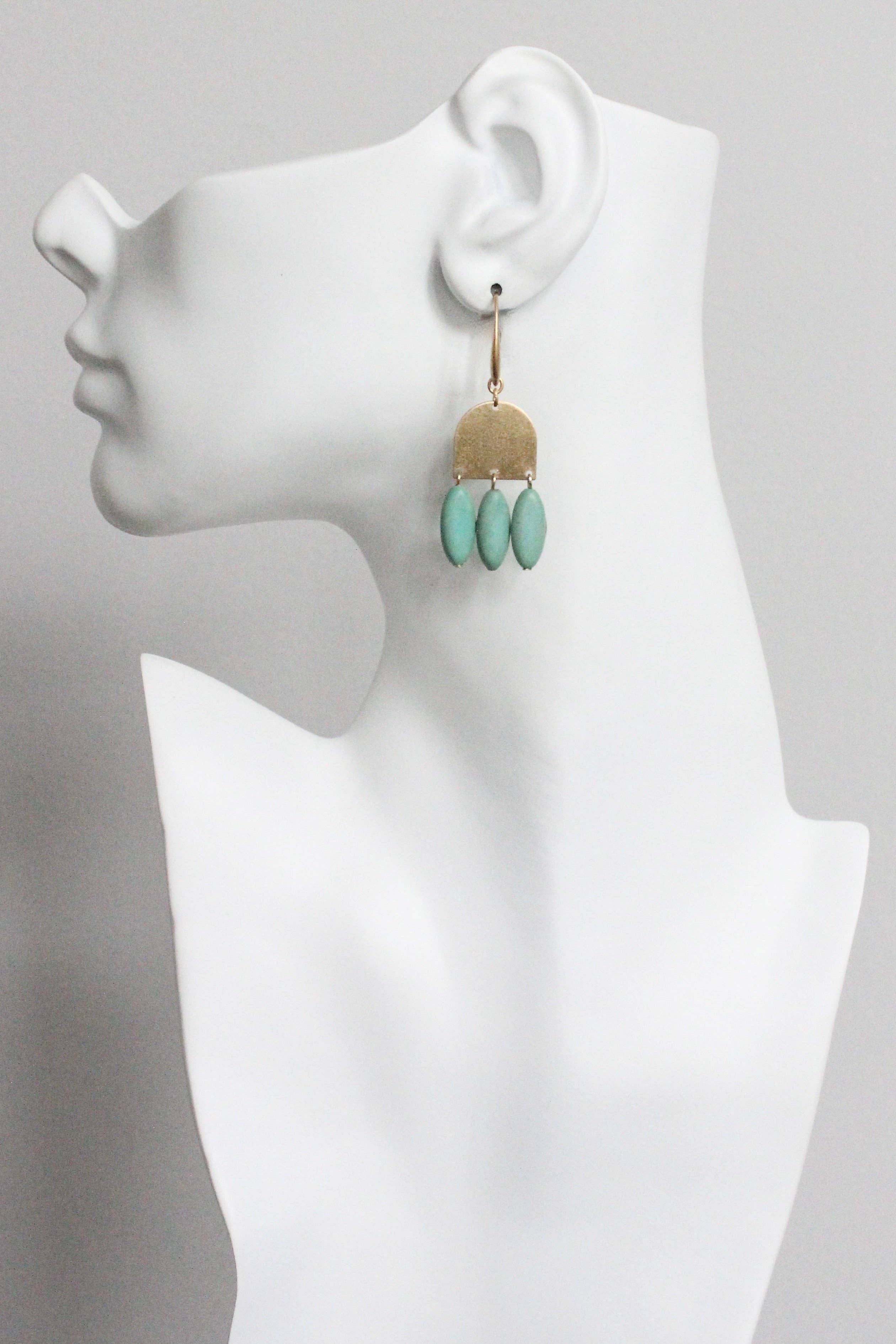 Earring displayed on a white mannequin bust with a gray background