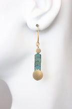 Earring with turquoise cylindrical bead and gold sphere on white background